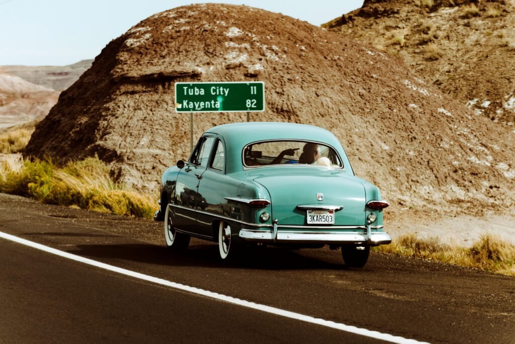 Classic vintage car driving through the scenic desert landscape of Arizona near Tuba City.